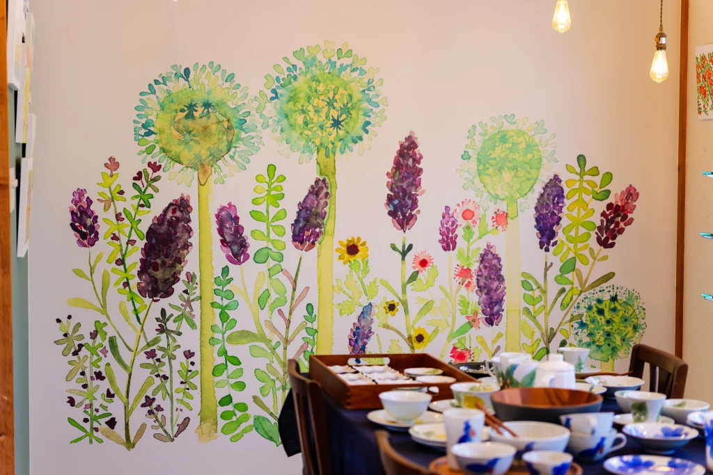 砥部焼 東窯の店内、草花の壁画と陶器の器が並ぶテーブル